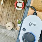 Ladestation für Elektrofahrzeuge an einer Holzwand mit Rettungsring und Seilrolle.