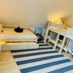 Zimmer mit Doppelbett, Krippenbett und gestreiftem Teppich