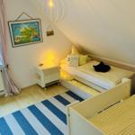 Zimmer mit zwei Betten, Fenster, Lampe und Wandbild.