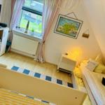 Schlafzimmer mit zwei Betten, Fenster, Schrank und Wandbild.