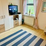 Schlafzimmer mit TV, Schrank und Fenster mit Blick auf Grün.