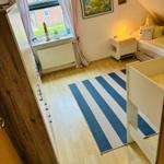 Schlafzimmer mit Kinderbett, Bett, Kleiderschrank und Fenster mit Blick auf Außenbereich.