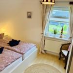 Schlafzimmer mit Doppelbett, Fenster, Vorhang und Sitzgelegenheit.