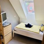 Ein Schlafzimmer mit Dachschräge, Bett, TV und Fenster.