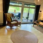 Wohnzimmer mit Sitzgelegenheiten und Balkonzugang. Holzboden und runder Teppich.