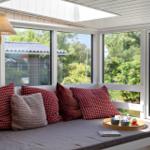 Seating bench with cushions and tray by window with garden view