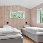 Two beds in a wooden room with windows and white bedding.