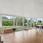 Large living and dining area with wooden floor and large windows overlooking the garden.