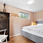 Bedroom with wooden walls, bed, wardrobe, and chair.