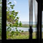 Durch ein Fenster blickt man auf einen See und das Meer.