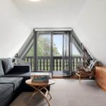 Wohnzimmer mit Sofa, Couchtisch und Blick auf Balkon.