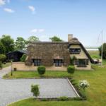 Haus mit Strohdach, Garten und Blick aufs Wasser.