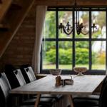 Esszimmer mit Holztisch, schwarzen Stühlen und großem Fenster mit Blick auf Garten