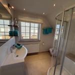 Badezimmer mit Dusche, Waschbecken und Fenster
