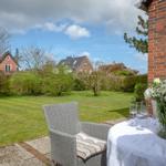 Terrasse mit Tisch, Stühlen und Blumenarrangement. Blick auf grünen Garten und Nachbarhäuser.