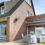 Haus mit Terrasse, Gartenmöbeln und Strandkorb. Zwei Fenster im Dachgeschoss.