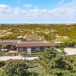 House with terrace and garden, surrounded by dunes and sea.