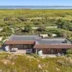 Ein Haus mit Terrasse und Garten, umgeben von Grünflächen und einem Wasserbereich.