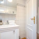 Badezimmer mit Waschbecken, Spiegel und Duschbereich.