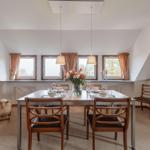 Esszimmer mit Tisch, Stühlen und Fenstern. Dekoration mit Blumen und Kerzen.