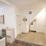Eingangsbereich mit Garderobe, Uhr und Bild an der Wand.