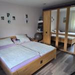Schlafzimmer mit Doppelbett, Kleiderschrank und Wandbildern.