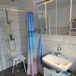 Badezimmer mit Dusche, Waschbecken und Spiegelschrank. Duschvorhang und Handtuch hängen.