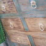 Antik lackierter Schrank mit Metallgriffen und Pflanze daneben