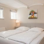 Schlafzimmer mit Bett, zwei Nachttischen und Wandbild einer Kuh.