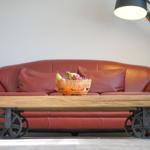 Roter Ledersofa mit Korb voller Früchte und industrieller Couchtisch mit Rädern.