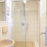 Bad mit Dusche, Waschbecken und Spiegel