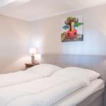 Schlafzimmer mit Bett, Nachttischen und Wandbild einer Kuh.