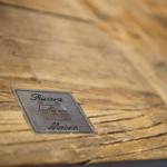 Metallplakette mit Hauszeichen auf Holzoberfläche