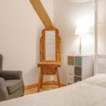Schlafzimmer mit Bett, Sessel, Spiegel und Nachttisch.