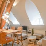 Wohn- und Essbereich mit Holzdecke, Tisch, Stühlen und Sofa.