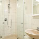 Badezimmer mit Dusche, Waschbecken und Spiegel