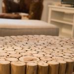 Holztisch aus Baumstämmen im Wohnzimmer mit Sitzbank und Fernsehregal im Hintergrund.
