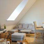 Wohnbereich mit Sofa, Sitzbank und Fernseher unter Dachschräge