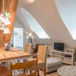 Dachgeschosswohnung mit Essbereich, TV und Sitzgelegenheiten unter schrägen Dachfenstern.