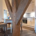 Küche mit Essbereich und massivem Holzpfosten im Vordergrund.