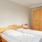Schlafzimmer mit Holzbett, Nachttischen und Kleiderschrank.