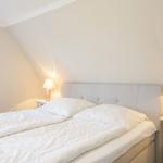 Ein Schlafzimmer mit Doppelbett, zwei Nachttischen und einem Fenster.