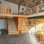 Eingangsbereich mit Holztreppe, hölzernen Türen und rustikalem Bodenbelag.