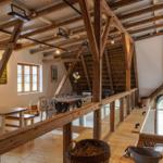 Großes Wohnzimmer mit Holzdecke, Tisch und Stühlen, Fenster und Sicht auf Außenbereich.
