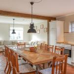 Essbereich mit Holztisch und Stühlen. Küche mit weißen Schränken. Wohnzimmer im Hintergrund.