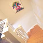 Haus mit Holztreppe und farbigem Wandbild einer Kuh