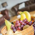 Eine Schale mit Obst steht im Vordergrund. Im Hintergrund ist ein Sofa zu sehen.