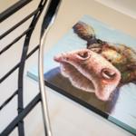Ein Wandbild mit einem Kuhkopf, das an einer Wand neben einem Metallgeländer hängt.