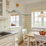 Küche mit Essbereich, weißen Möbeln und Fenstern zum Blick ins Freie.