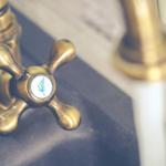 Goldener Wasserhahn mit Markenlogo auf dunklem Waschbeckenrand.